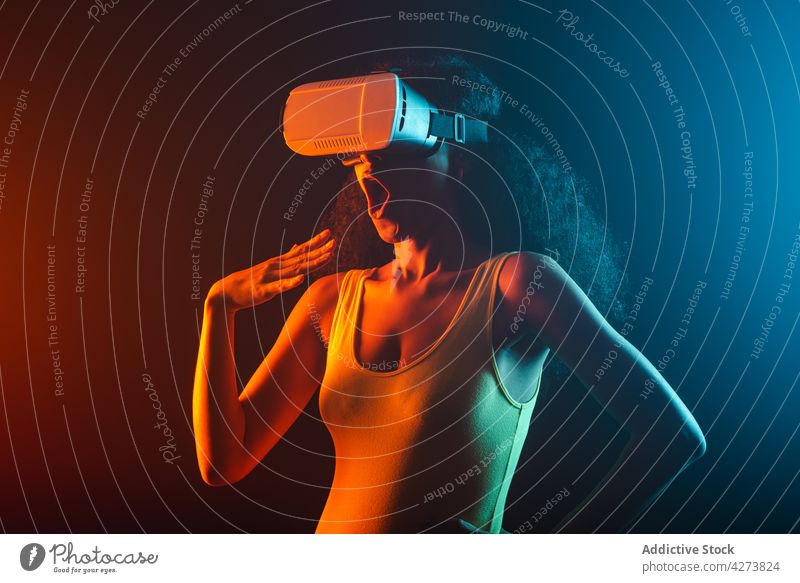 Unrecognizable amazed black woman experiencing virtual reality in goggles vr neon entertain immerse technology astonish mouth opened using gadget device explore