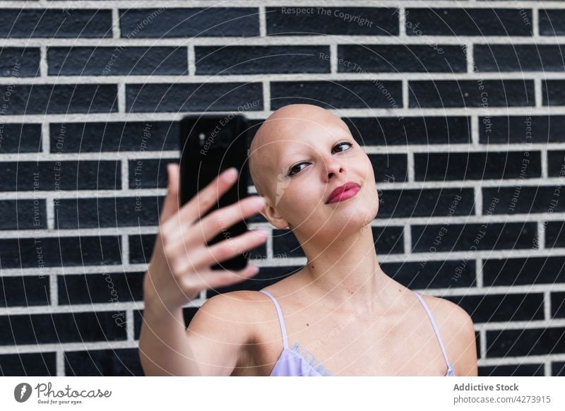 Cheerful young bald female millennial smiling and taking selfie on smartphone woman alopecia disease optimist cheerful confident social media mobile hairstyle
