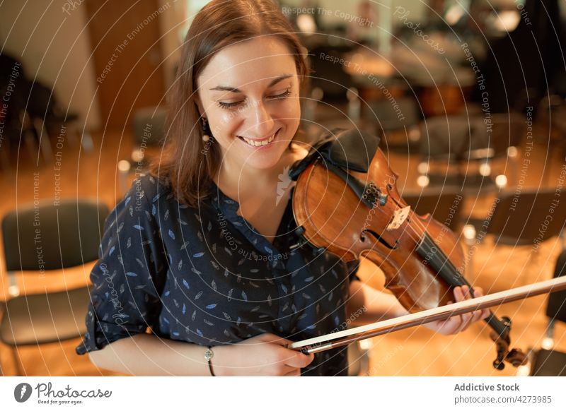 Happy female violinist performing classical music in hall woman musician play smile happy delight rehearsal instrument skill toothy smile melody glad cheerful