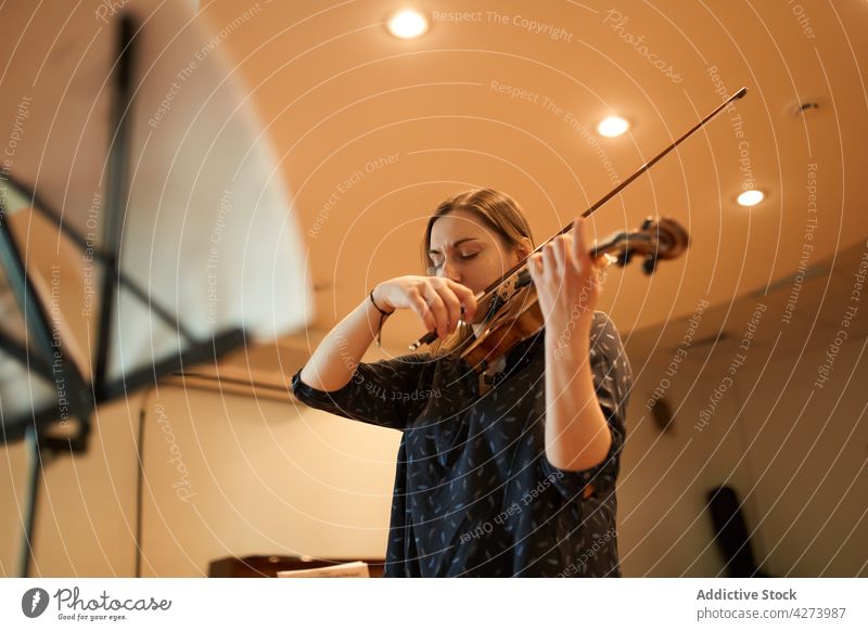 Female violinist performing classical music in hall woman musician play rehearsal instrument skill melody sound eyes closed talent enjoy studio acoustic audio