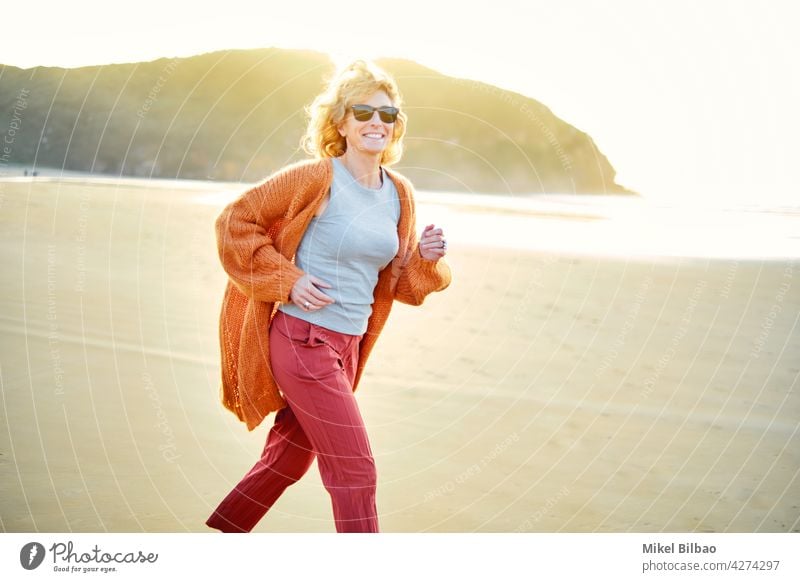 Young mature blonde caucasian woman running outdoor in a beach in a sunny day.  Lifestyle concept. lifestyle portrait wellness women healthy joyful active