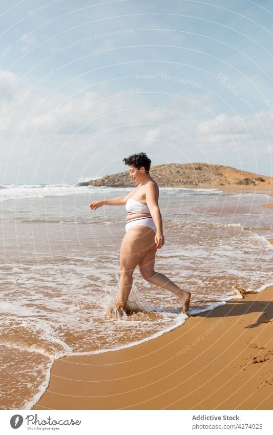 Woman standing on ocean water on sandy beach woman sea plus size swimsuit blue sky having fun shore alone female young foam tourist seashore harmony daytime