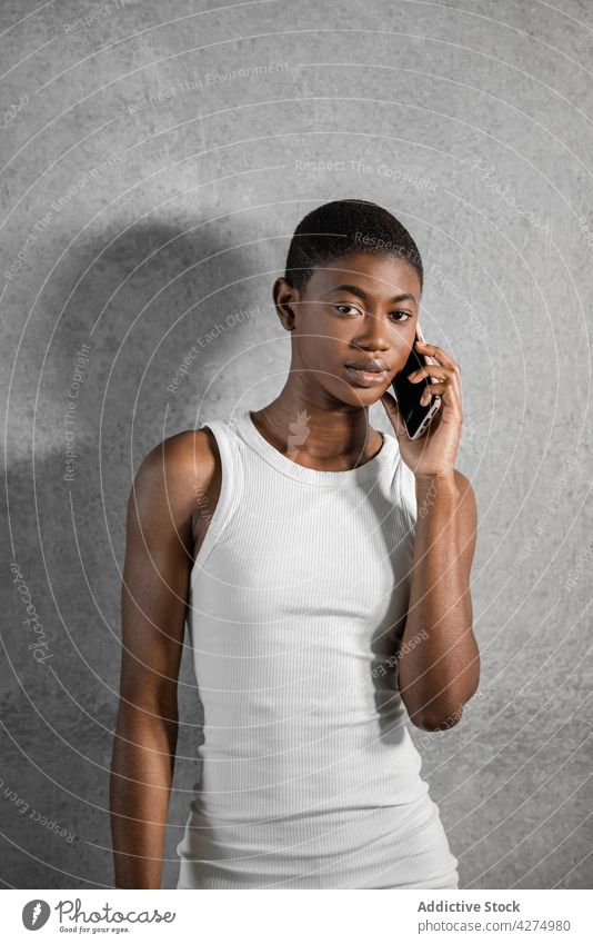 Stylish black model talking on smartphone on gray background speak fashion style individuality feminine phone call woman using gadget device cellphone