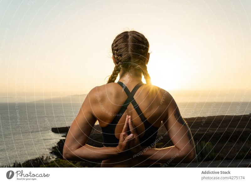 Unrecognizable woman with praying hands behind back against sea namaste hand behind back yoga practice stretch greeting wellness sunshine symbol coast ocean