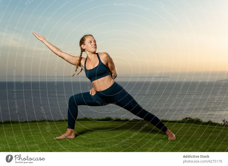 Woman performing Crescent Lunge pose on sea shore woman crescent lunge yoga outstretch flexible wellness healthy lifestyle touch thigh seashore evening