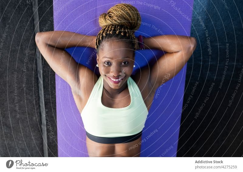 Smiling black sportswoman exercising on mat in gym athlete cheerful hand behind head workout training exercise portrait strong smile body wellbeing