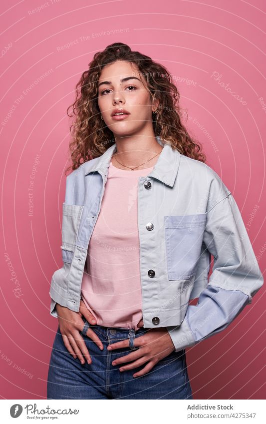 Cool youngster standing in studio woman style posture carefree millennial appearance female portrait curly hair hairstyle charming long hair casual personality