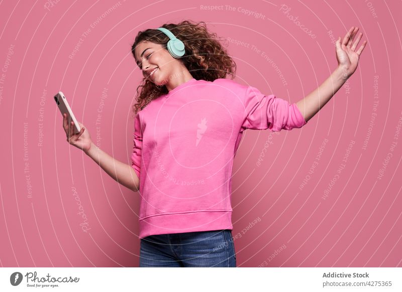 Smiling woman listening to music and using smartphone headphones jump enjoy vivid cool female happy cheerful teenage pleasure device wireless energy internet