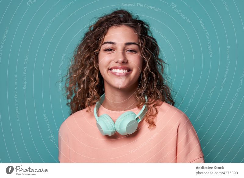 Smiling woman with headphones on neck in studio charming personality gadget vivid positive teenage cool female smile happy cheerful portrait bright young glad