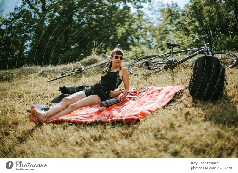 young woman relaxing on field adult attractive beautiful bicycle bike blanket carefree casual caucasian cheerful chic chilling cute elegant eyewear female