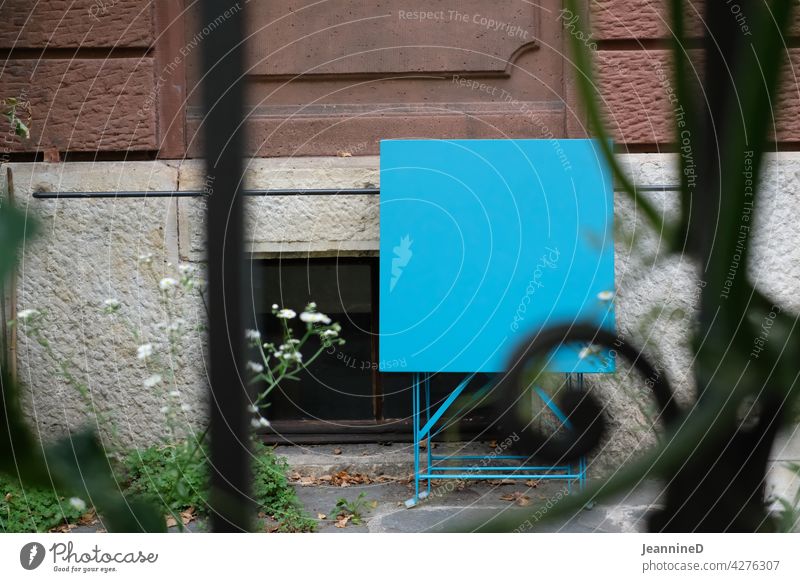View through metal garden fence with blue metal table folded against house facade Fence Garden Colour photo City life Town house (City: Block of flats)