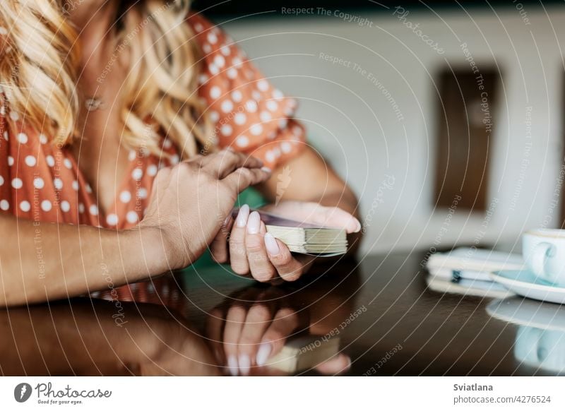 Close-up of a woman's hands with tarot cards in a cafe at a table having art predictions professional psychic psychological read relaxation sitting in a cafe
