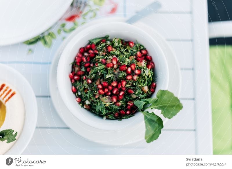On the table in an Arab restaurant there is a parsley tabbouleh salad with pomegranate seeds. View from above. healthy green arabic food tabouleh healthy salad
