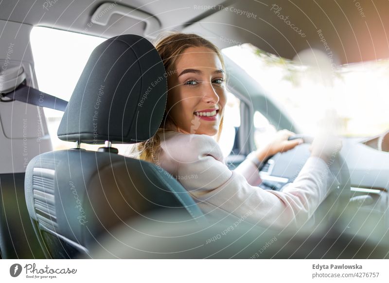 Young woman driving a car carsharing confident smiling satisfaction female attractive beautiful young adult joy positive content sitting driver owner transport