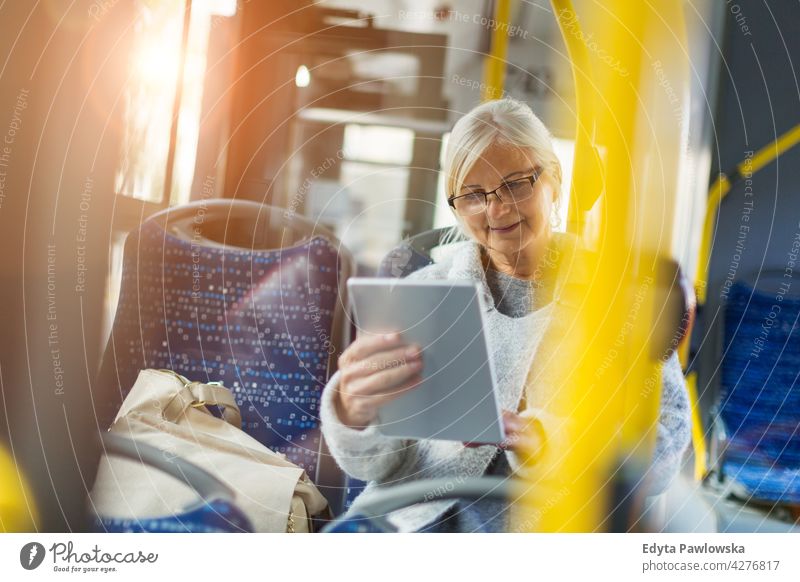 Senior woman using tablet, while riding public bus senior seniors pensioner pensioners casual outdoors one person retiree retired outside retirement aged old