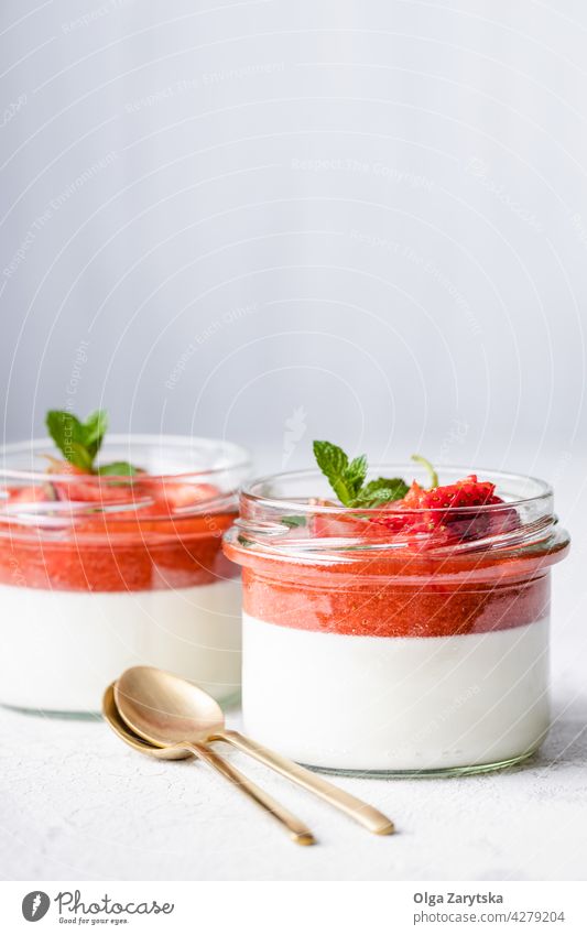 Panna cotta in glass jars with strawberry sauce. panna cotta milk dessert pudding jelly mint table spoon two white sweet fresh creamy leaf italian red fruit