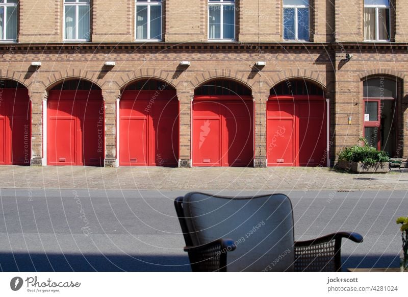 Seat in front of the fire station Firehouse Chair back Brick facade Arch Garage door Highway ramp (exit) Sidewalk Symmetry Architecture Highway ramp (entrance)