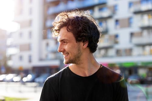 Portrait of a handsome young man in the city sunny outside curly hair hipster person adult confidence outdoors summer male attractive natural one portrait