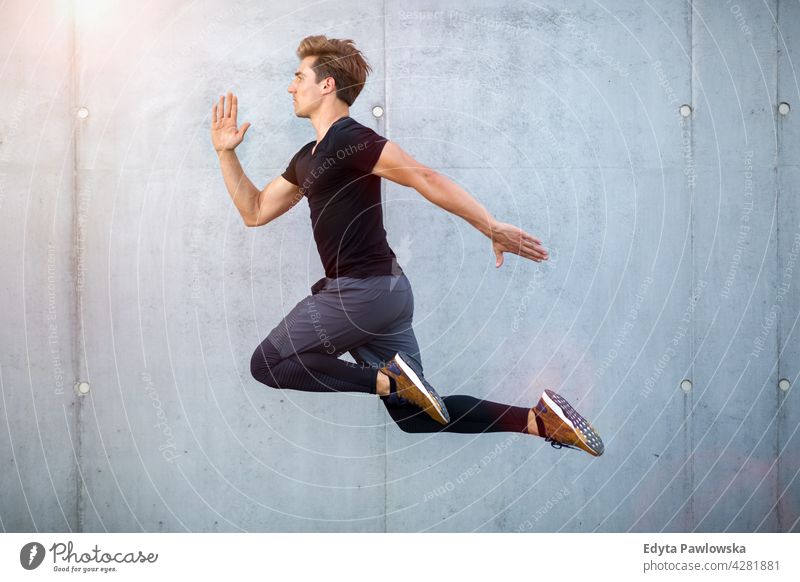 Handsome young man jumping against grey wall people person guy fashionable serious sexy fit slim body hair style standing one stylish caucasian boy expression