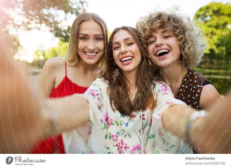 Three friends taking selfies sunset summer group together people woman women young casual beautiful attractive girl girls female three people friendship smiling