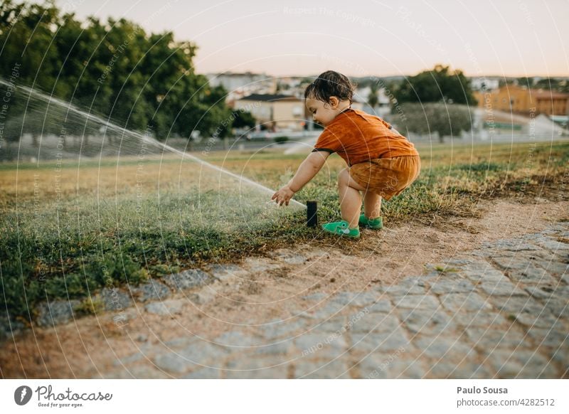 Child playing with water sprinkler childhood Caucasian 1 - 3 years Summer Grass Water Sprinkler system having fun Wet Nature Exterior shot Joy Playing Day