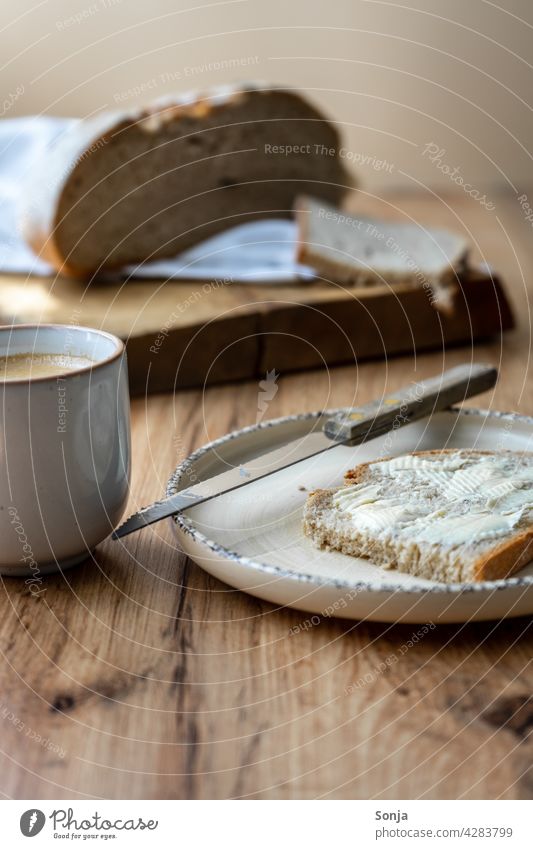 Breakfast table with a cup of coffee and a slice of bread with butter Slice of bread Butter Coffee Coffee cup Plate Wooden table Rustic Knives Morning Close-up