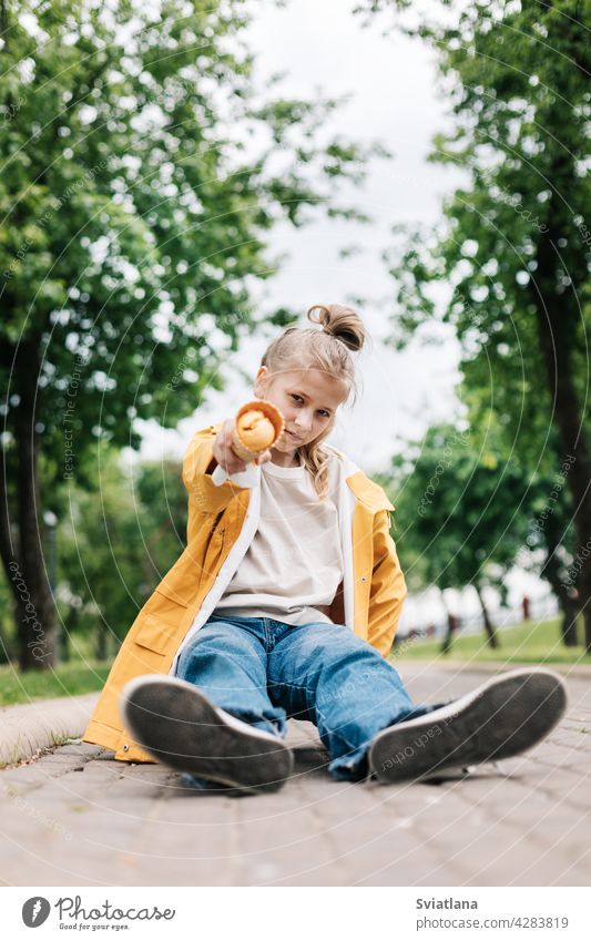 Portrait of a cute blonde teenage girl with ice cream on a walk in the park. Child outdoors summer teenager yellow funny trend happy child kid little dessert