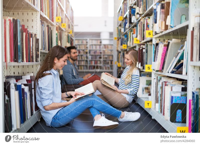 College students in a library enjoying lifestyle young adult people casual caucasian positive happy smiling woman female attractive beautiful bookstore reading