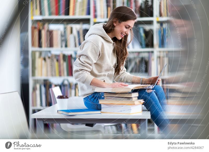 Young female student studying in the library enjoying lifestyle young adult people one person casual caucasian positive happy smiling woman attractive beautiful