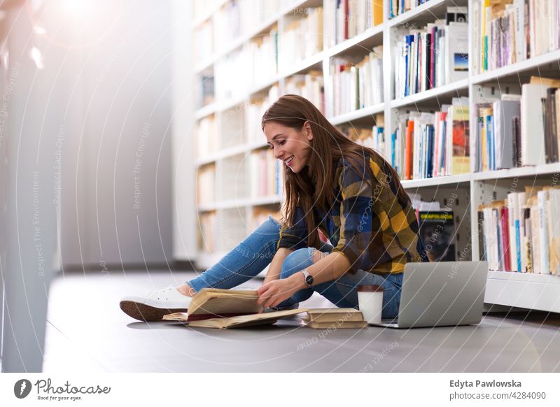 Young female student in a university library enjoying lifestyle young adult people one person casual caucasian positive happy smiling woman attractive beautiful