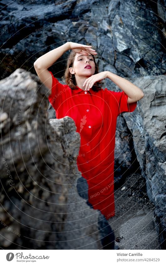 An elegant fashionable fresh beautiful woman in a red vintage dress with rocks background. portrait beauty young model hair face person cute wall smiling smile