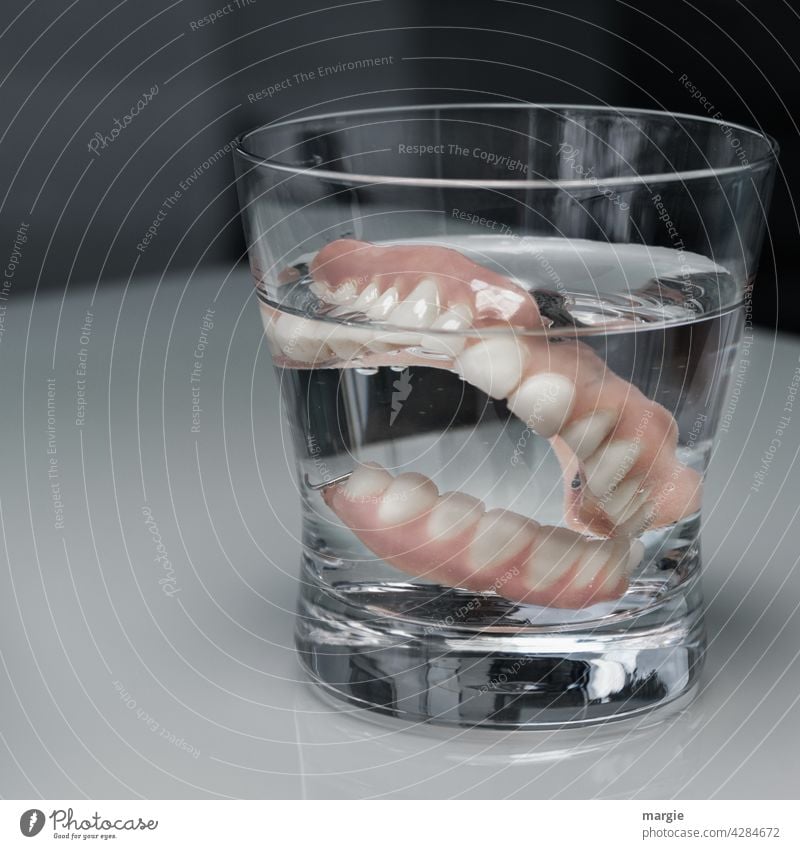 Dentures (teeth) in a glass of water Dental implant Set of teeth Dentistry Healthy Teeth Mouth care Close-up Laboratory dental health senior citizens age
