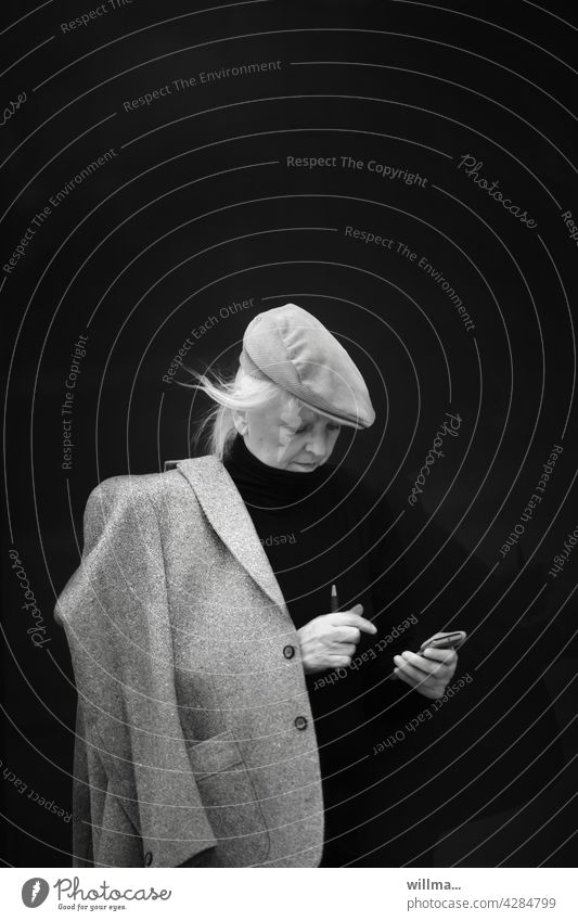 Woman with jacket and cap checks her appointments, businesswoman, business, modern communication sliding cap smartphone iPhone Cellphone Mobile Read message