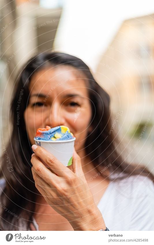 hispanic woman holding a cup of rainbow colored ice cream icecream hand eating fresh street food people smartwatch hands fruit lgbt colours pride young