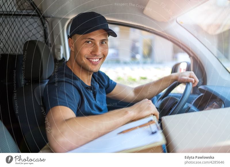 Delivery man sitting in a van delivery van car driver truck people young adult male smiling happy blue collar Courier dispatch rider delivery man delivering