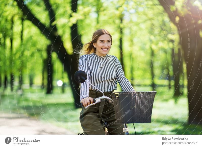 Young woman cycling through the park green trees nature freshness enjoying lifestyle young adult people casual caucasian positive happy smiling female