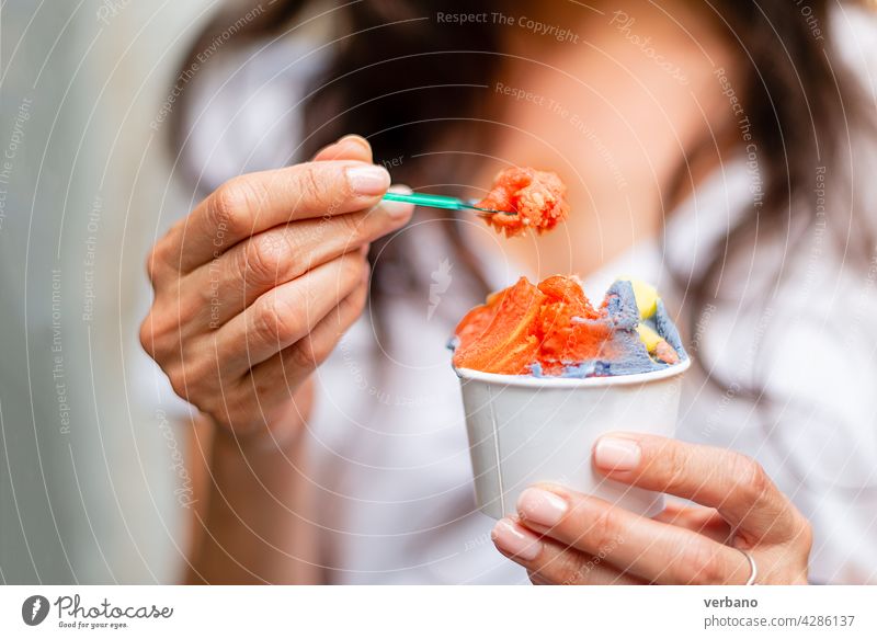 woman holding a cup of rainbow colored ice cream icecream hand eating hispanic fresh street food people smartwatch hands fruit lgbt colours pride young
