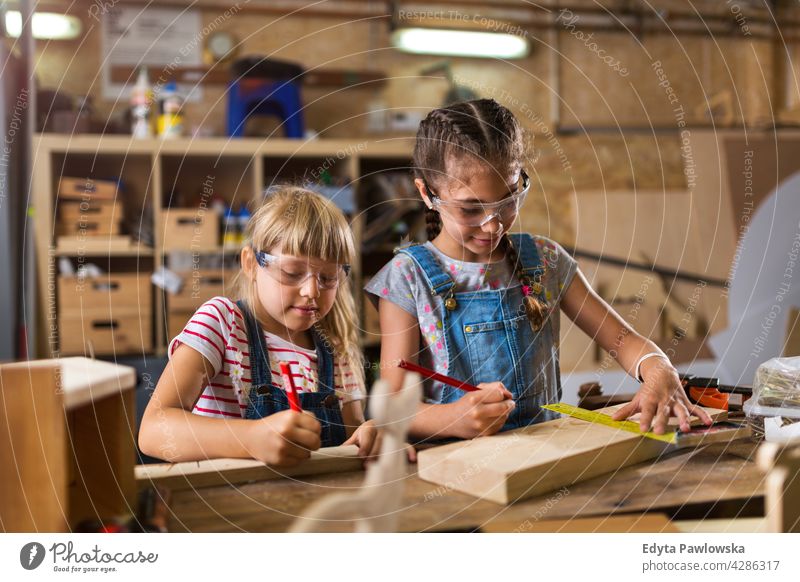 Two young girls doing woodwork in a workshop working people child children kid kids girl power Skill craft Garage Hobby Lifestyle tools Concentration Creativity