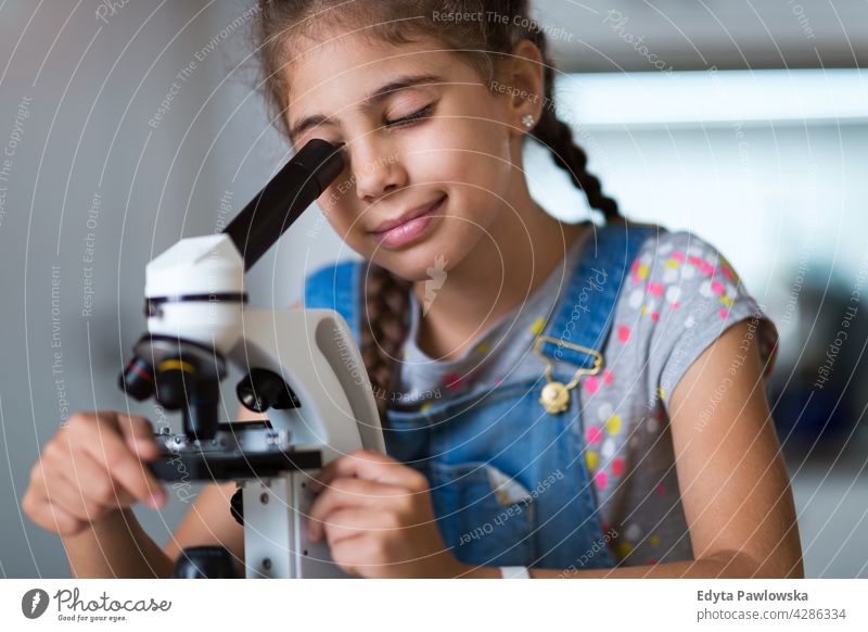 Young girl looking through microscope science workshop learning people child children kid kids Skill Lifestyle Concentration Caucasian Childhood desk Education
