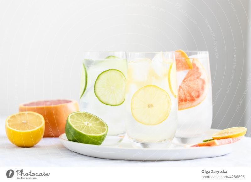 Three glasses with cold citrus water. drink lemonade ice grapefruit lime summer refreshment perspiration set beverage three white tablecloth minimal cocktail