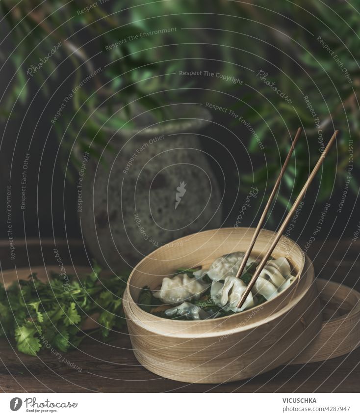 Asian food still life with bamboo steamer and homemade dumplings on rustic table. front view health healthy food fresh steamed vegetable dumplings chopsticks