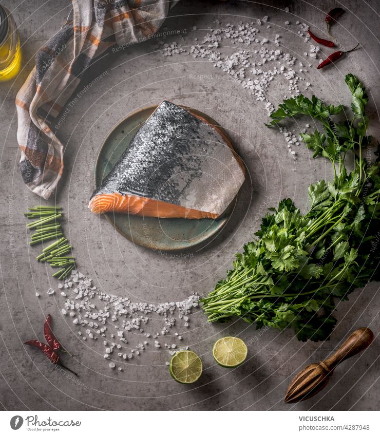 Raw salmon with chili, salt and lemon. Circle shaped ingredients and kitchen equipment. Grey concrete background. Top view . Healthy seafood concept copy space