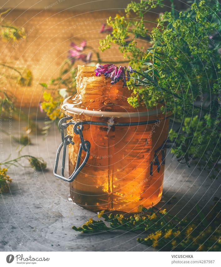 Close up of honey jar with honeycomb and fresh flowers. Still life front view wild flowers copy space honeycombs dark concrete background healthy nutrition