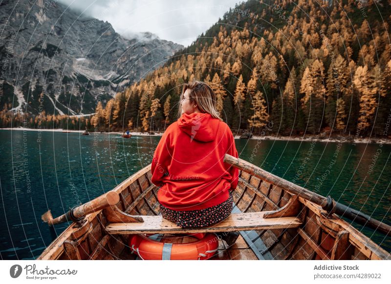 Anonymous woman on boat in dolomite lake forest glacier water tourism mountain landscape cold beautiful travel nature green park alps blonde scenery europe