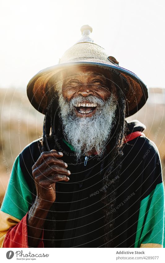 Serene hippie rastaman standing on field rastafarian african happy smile male delight cheerful culture ethnic reggae caribbean nature african american native