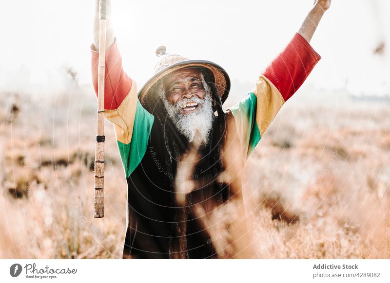 Happy hippie rastaman standing on field rastafarian happy smile male delight cheerful culture ethnic reggae excited caribbean victory nature eyes closed