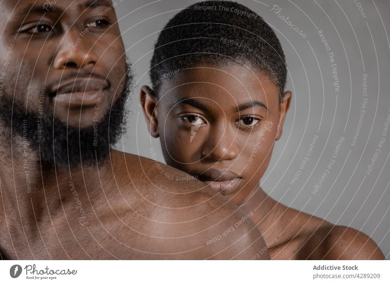Enamored young shirtless African American couple hugging in studio embrace love romantic relationship together tender affection portrait close fondness model