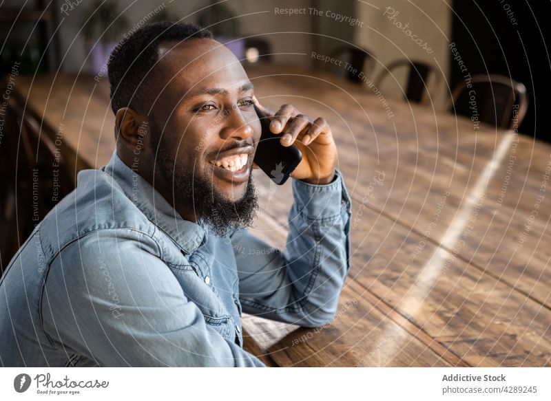 Smiling young black guy talking on smartphone man phone call smile positive communicate conversation cheerful connection discuss glad content male ethnic