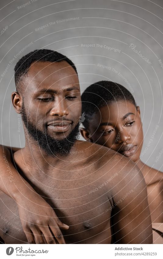 Enamored young shirtless African American couple hugging in studio embrace love romantic relationship together tender affection portrait close fondness model