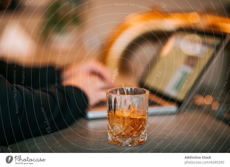 Person working on laptop with glass of whiskey person employee using orange busy typing freelance internet device brandy gadget surfing slice online browsing